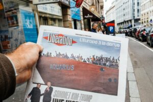 A man buys the newspaper Libe with a news piece on the Aquarius